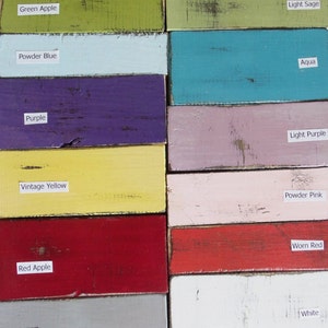 May include: A color chart with 14 different paint colors, including apricot, green apple, powder blue, purple, vintage yellow, red apple, gray, brown, black, light sage, aqua, light purple, powder pink, and white. The colors are displayed in two columns, with the names of the colors written below each swatch.