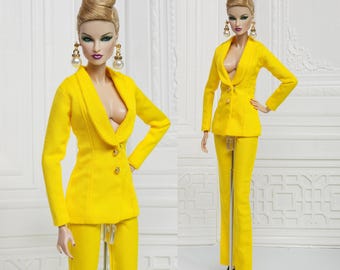 May include: A yellow suit with a blazer and pants. The blazer has a deep V-neck and gold buttons. The model is wearing pearl earrings.