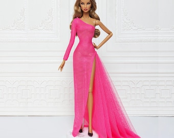 May include: A pink one-shoulder gown with a sheer bodice and a long train. The gown has a thigh-high slit and is made of a sparkly fabric.
