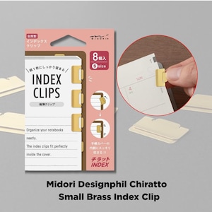 May include: A package of Midori Designphil Chiratto small brass index clips. The package is pink and white, with the text "INDEX CLIPS" and "8 size" printed on it. The image shows the clips in use, attached to the edge of a notebook page.