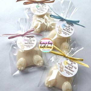 May include: Bunny-shaped handmade soap bars in clear cellophane bags, tied with pastel ribbons. Each soap has a round tag with a bunny illustration and the text "Thank you for hopping by Grace's Baby Shower! handmade soap."