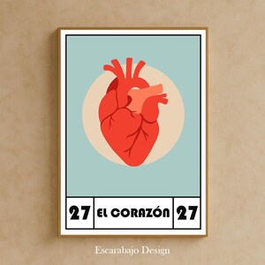 Puede incluir: Impresión enmarcada con una ilustración de corazón rojo estilizado sobre un fondo azul claro. El número 27 enmarca la frase en español "EL CORAZÓN". El nombre del artista, Escarabajo Design, se encuentra en la parte inferior.