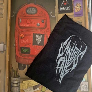 Może przedstawiać: Czarna naszywka z białym, stylizowanym logo i czerwony plecak z różnymi naszywkami i tekstem, w tym "DEADTONES" i "CREEPER". Plecak jest ozdobiony grafiką w stylu graffiti.