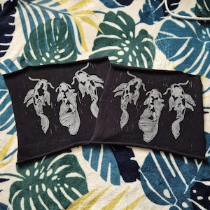 May include: Two black fabric panels with white ink prints of koi fish. The panels are on a patterned fabric background.