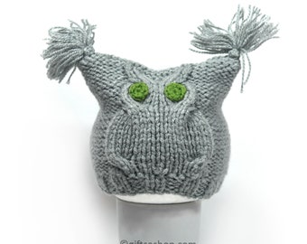 May include: Gray knitted owl hat with green felt eyes and two long gray yarn tassels on top.