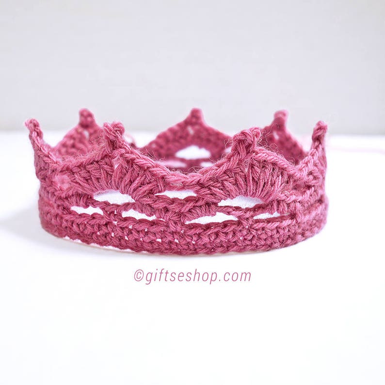 May include: A pink crocheted crown with a delicate, intricate design. The crown is made with a soft, yarn and has a delicate, feminine look.