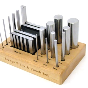May include: A set of metal swage blocks and punches in a wooden holder. The set includes a variety of sizes, from 2mm to 11mm. The holder has a label that reads "Swage Block & Punch Set".