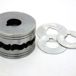 May include: A silver metal tool with a wavy edge and three flat, round pieces with a hole in the center.