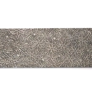 May include: A silver metal sheet with a repeating pattern of small, embossed flowers. The flowers are arranged in a random pattern and are all the same size.