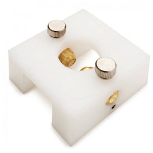 May include: White plastic device with two silver knobs and three brass fittings. The device has a square base and a rectangular opening in the centre.