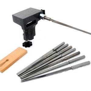 Puede incluir: Una herramienta de metal con una base de madera y un juego de ocho limas de metal. La herramienta se utiliza para afilar y dar forma a objetos de metal.
