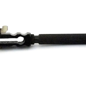 May include: A black metal hand-held vise with a knurled handle and a wing nut. The vise has a small opening for holding small objects.