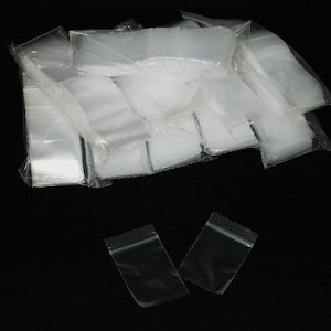 May include: A stack of clear plastic bags with a zipper closure. The bags are arranged in a pile and are ready to be used for packaging or storage.