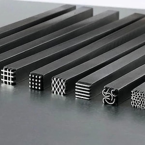 May include: A set of ten metal stamping tools with different designs. The tools are arranged in a row on a silver surface. Each tool has a square head with a unique pattern.