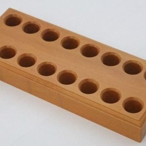 May include: A wooden storage organizer with 12 round holes for holding small items. The organizer is made of light brown wood and has a rectangular shape.
