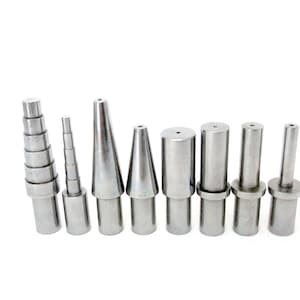 May include: Set of ten metal mandrels for jewelry making, including a graduated mandrel with multiple sizes. The mandrels are silver in color and have a variety of shapes, including round, conical, and tapered.