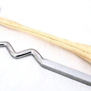 Puede incluir: Un martillo de metal plateado con mango de madera y una herramienta de modelado de metal plateado con un diseño ondulado.