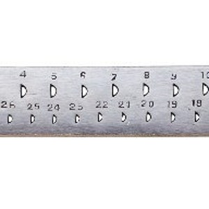 Puede incluir: Una regla de metal con agujeros numerados del 1 al 13, con tamaños correspondientes en milímetros, que van de 30 a 14. La regla está marcada con "STELLA".