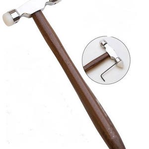 May include: A wooden-handled hammer with two white rubber heads. The hammer is used for shaping metal.
