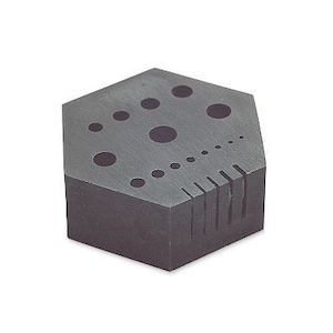 May include: A hexagonal grey stone tool with various sized holes and grooves. The tool is designed for sharpening and shaping tools.