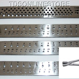 May include: Four metal rulers with different sized holes and markings. The rulers are labelled "LIBERTY" and have numbers from 1 to 18. The rulers are used for measuring and sizing jewellery. The rulers are next to a pair of silver metal pliers.
