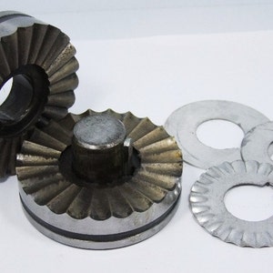 May include: Two silver metal gears with a serrated edge and a centre hole. Three silver metal washers with a serrated edge and a centre hole.