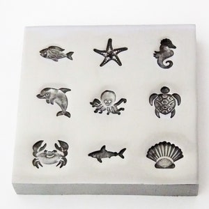 May include: A white rectangular silicone mould with nine different sea creature designs. The designs include a fish, starfish, seahorse, dolphin, octopus, turtle, crab, shark, and seashell.