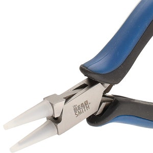 May include: Close-up of a pair of silver-toned pliers with blue and black handles. The pliers have white, silicone-tipped jaws and the text "The Beadsmith" is printed on the side.