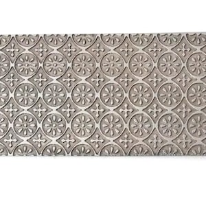 May include: A silver metal sheet with a repeating embossed pattern of circles and crosses. The pattern is a traditional design.