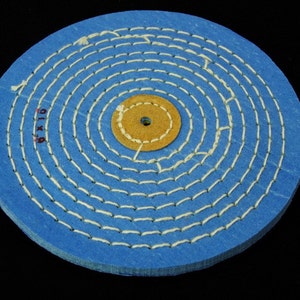 May include: A blue buffing wheel with a tan center and white stitching. The wheel is 8 inches in diameter.
