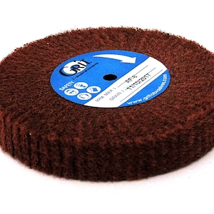 Puede incluir: Una rueda de lija redonda y marrón con una etiqueta azul que dice "Grit" y "AF-8 Grain: 1111072017" y una dirección de sitio web. La etiqueta también tiene un símbolo de seguridad con una mano apuntando hacia la derecha.