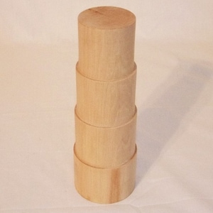 May include: A set of four wooden nesting boxes, stacked in a tower. The boxes are made of light-colored wood and have a smooth, natural finish.