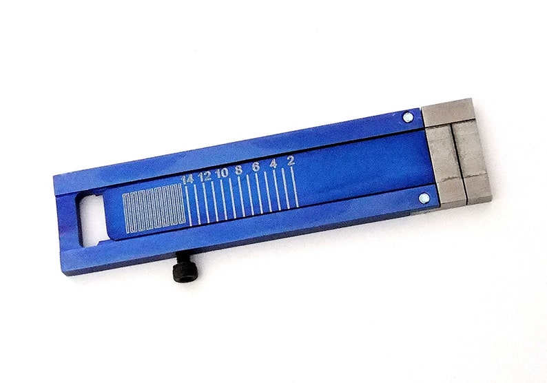 Puede incluir: Una regla de metal azul con una escala marcada en pulgadas de 2 a 14. La regla tiene un peque&ntilde;o agujero en el lado izquierdo y un tornillo en la parte inferior.