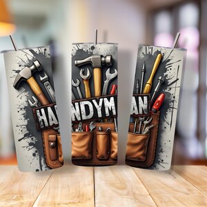 May include: Three stainless steel tumblers with a design of tools and the word "HANDYMAN" on a gray background with black paint splatters. The tools include a hammer, screwdriver, wrench, and pliers.
