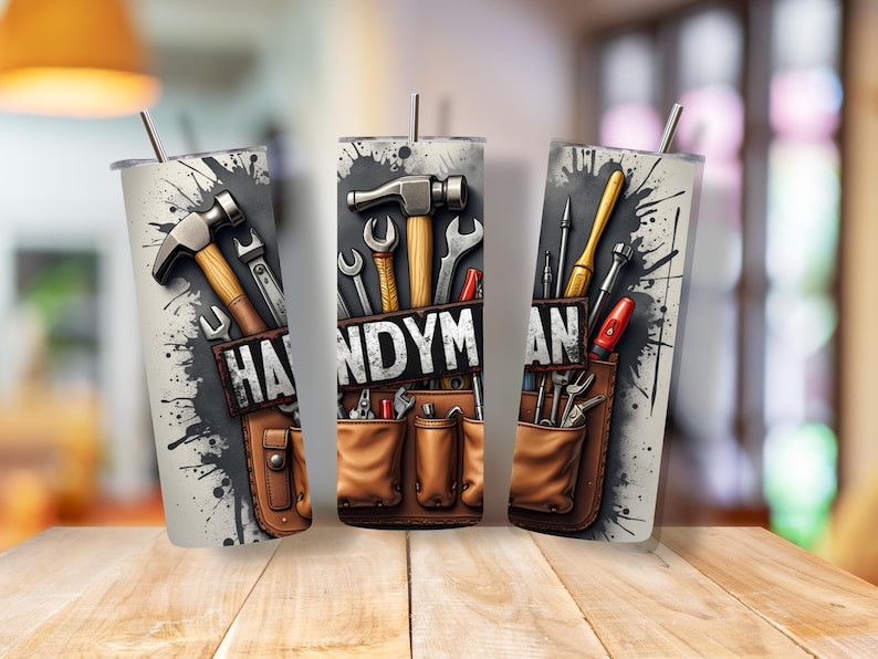 May include: Three stainless steel tumblers with a design of tools and the word "HANDYMAN" on a gray background with black paint splatters. The tools include a hammer, screwdriver, wrench, and pliers.