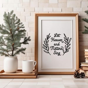 May include: A framed print with a black and white design of leafy branches and the text "Let Heaven and Nature Sing". The print is hanging on a white brick wall with a small potted evergreen tree on the left and a larger potted evergreen tree on the right.