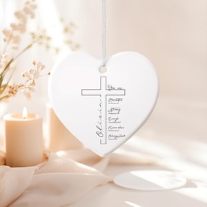 May include: A white heart-shaped ornament with a cross design and the name "Olivia" in a script font. The ornament includes the words "You are... Beautiful, Strong, Enough, Never alone, Always loved" in black text.