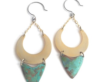 May include: A pair of gold and turquoise earrings with a crescent moon shape and a teardrop shape. The earrings are made of metal and have a rustic, handmade look.