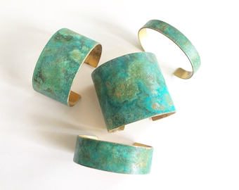 May include: Four brass bracelets with a turquoise patina finish. The bracelets are stacked on top of each other.