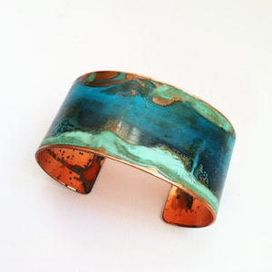 May include: A copper cuff bracelet with a turquoise and green marbled design.