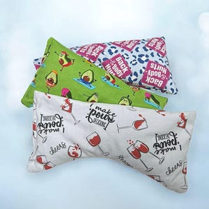 May include: Three rectangular pillows with different patterns. One has avocados doing yoga on a green background. Another has a blue and white leopard print with the text "Back & Body Hurts." The third has wine glasses and the text "I make pour decisions."