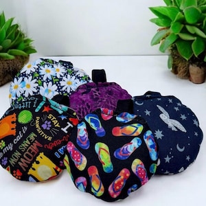 May include: A collection of five round fabric items with various patterns. Designs include white daisies on navy, colorful flip-flops on black, a cat-themed print, a purple leopard print, and a navy print with a rabbit and stars.