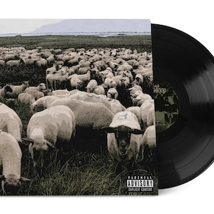 Puede incluir: Un disco de vinilo negro junto a su portada. La portada presenta una imagen en tonos sepia de una gran manada de ovejas en un campo. La portada del álbum tiene el texto "Parental Advisory Explicit Content".