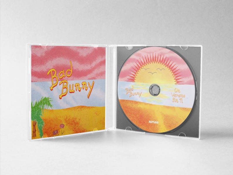 May include: A CD case open, revealing a disc and cover art. The cover art features the text "Bad Bunny" in yellow script over a desert landscape with a sunset. The CD itself has a similar design.