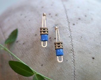 Peut inclure: Une paire de boucles d'oreilles bleues et dorées avec un design géométrique. Les boucles d'oreilles sont en métal et ont une finition en émail bleu.