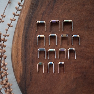 May include: A collection of 15 small, silver-toned resistors with colored bands. The resistors are arranged in three rows of five on a wooden surface.