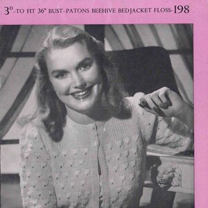 Peut inclure: Image en noir et blanc d'une femme portant un cardigan clair à boutons avec un motif texturé. Le texte en haut indique "3D-POUR S'ADAPTER 91cm DE POITRINE-PATONS BEEHIVE BEDJACKET FLOSS-198". Le logo P&B WOOLS est en bas.