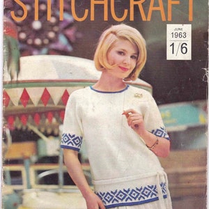 以下が含まれることがあります： 白地に青と白の幾何学模様のトリムが施された白いニットドレスを着た女性が写っている、ビンテージ雑誌の表紙。雑誌のタイトルは「Stitchcraft」、日付は1963年6月です。