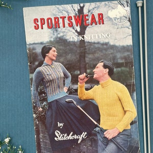 May include: A vintage knitting pattern booklet titled "Sportswear in Knitting" by Stitchcraft. The cover features a couple wearing knitted sweaters in a park setting.