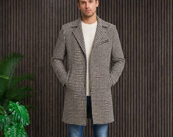 Könnte beinhalten: Ein langärmeliger Mantel mit schwarz-weißem Hahnentrittmuster, getragen über einem schlichten weißen Pullover und einer blauen Jeans. Der Mantel hat ein steigendes Revers, eine einreihige Knopfleiste, zwei Seitentaschen und weiße Sneaker.